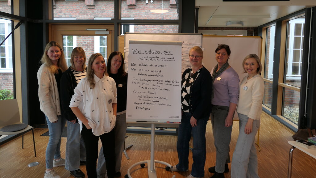 Gruppenbild von sieben Caritas-Mitarbeiterinnen, die um ein Flipchart stehen.