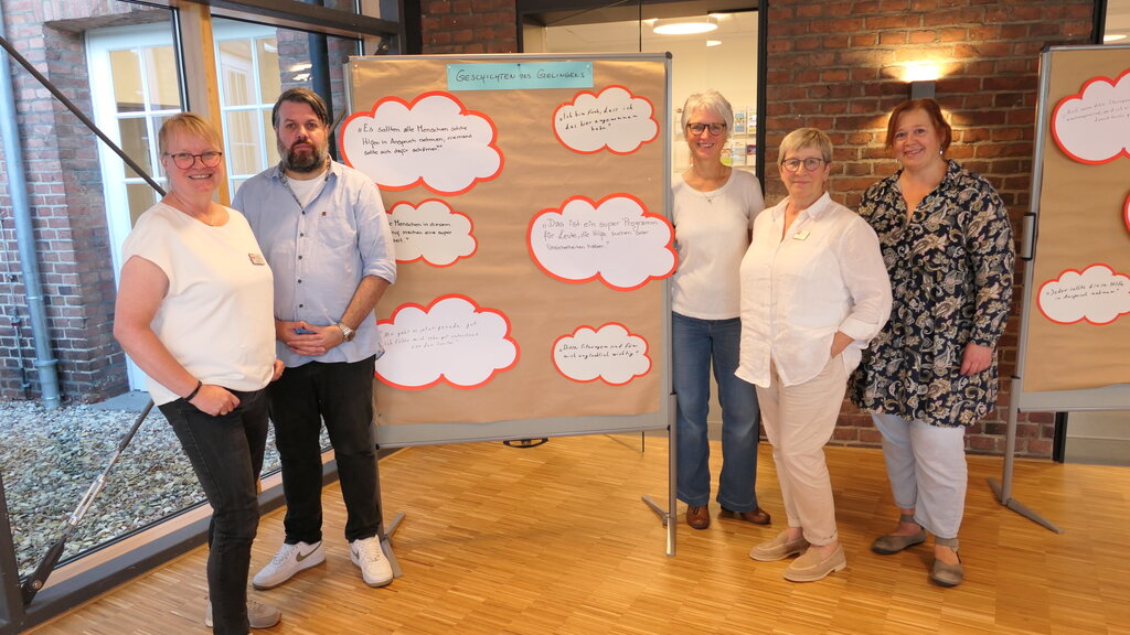 Gruppenbild mit fünf Referentinnen und Referenten vor einer Pinwand mit Sprechblasen
